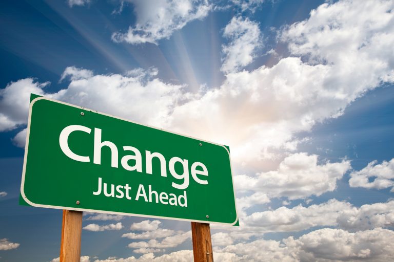 Green sign saying "change just ahead" with cloud background