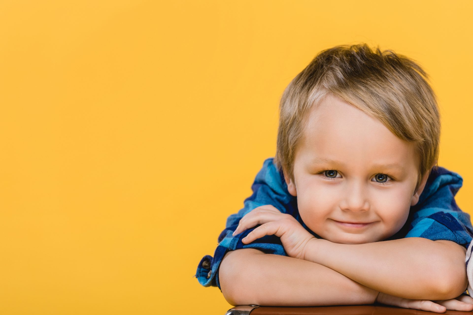 young boy smiling on yellow background