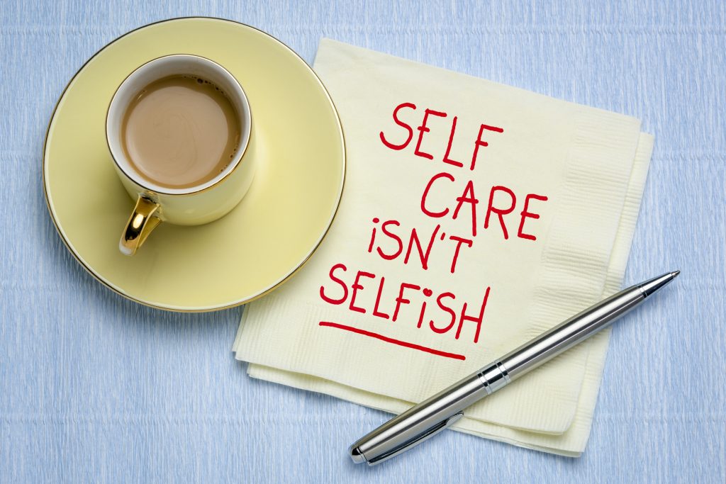 coffee cup with napkin with words "self care isn't selfish" written on it