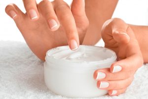 woman dipping finger into whipped moisturizing skin cream