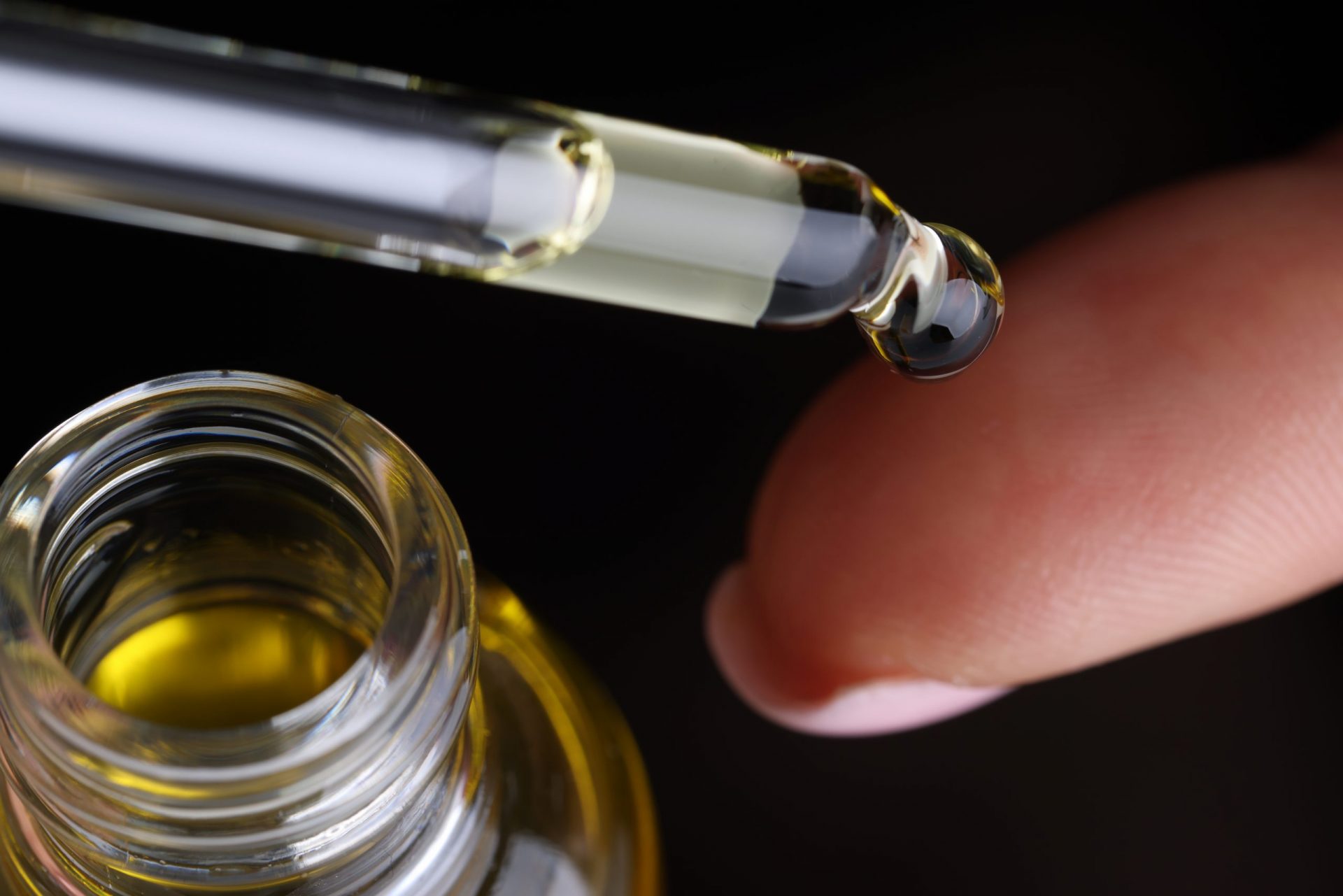 woman dosing CBD oil from dropper on to finger tip