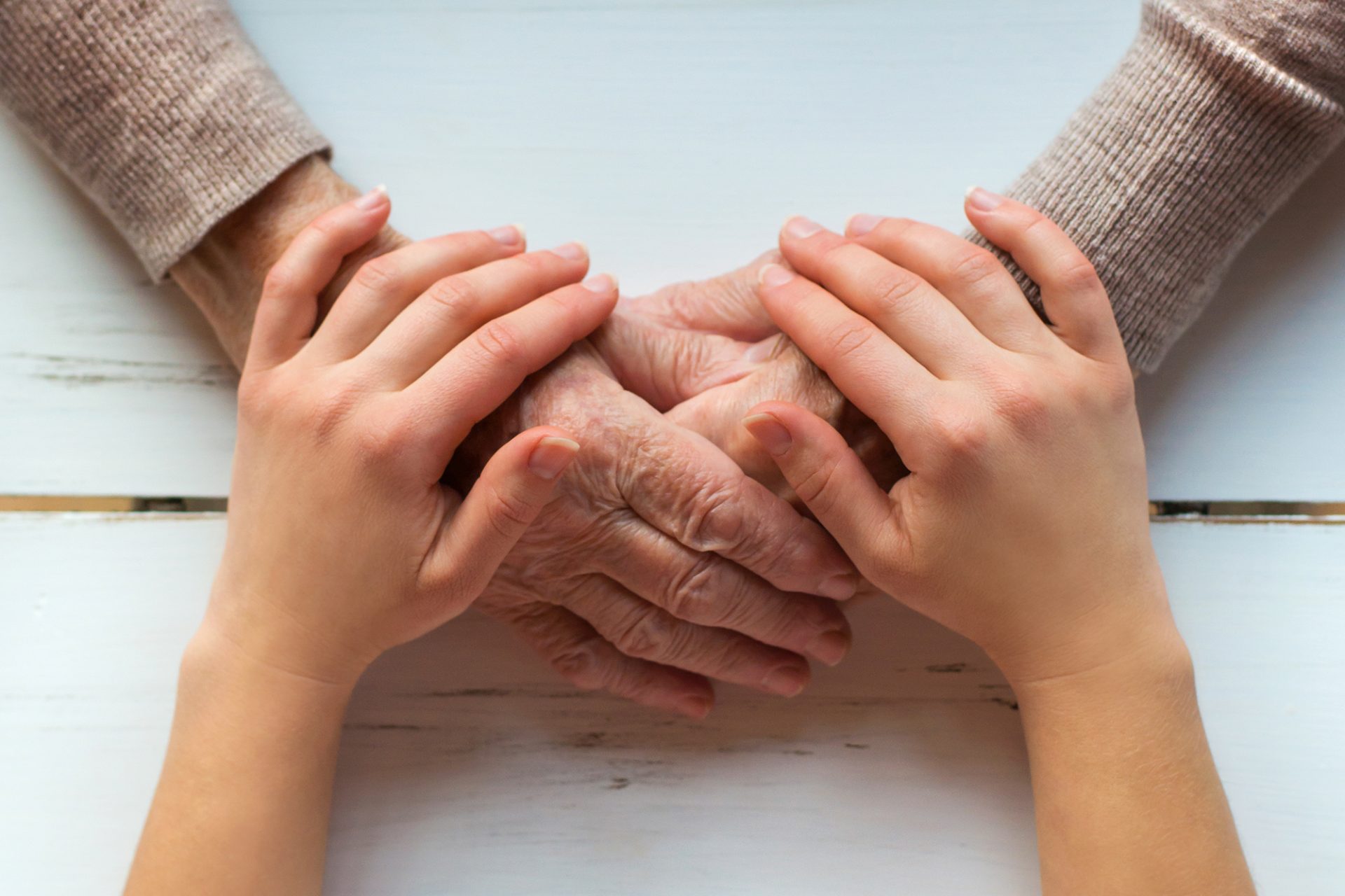young hands holding elderly person's hands