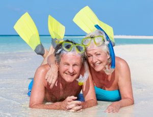 senior man and woman lying on beach with masks and fins